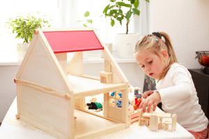 young caucasian girl playing with doll house in playroom during play therapy at balance and potential 30022
